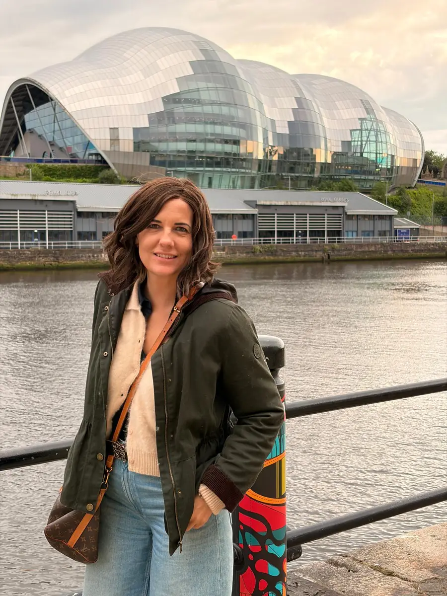 Esther junto a un río, con un edificio de cristal al fondo