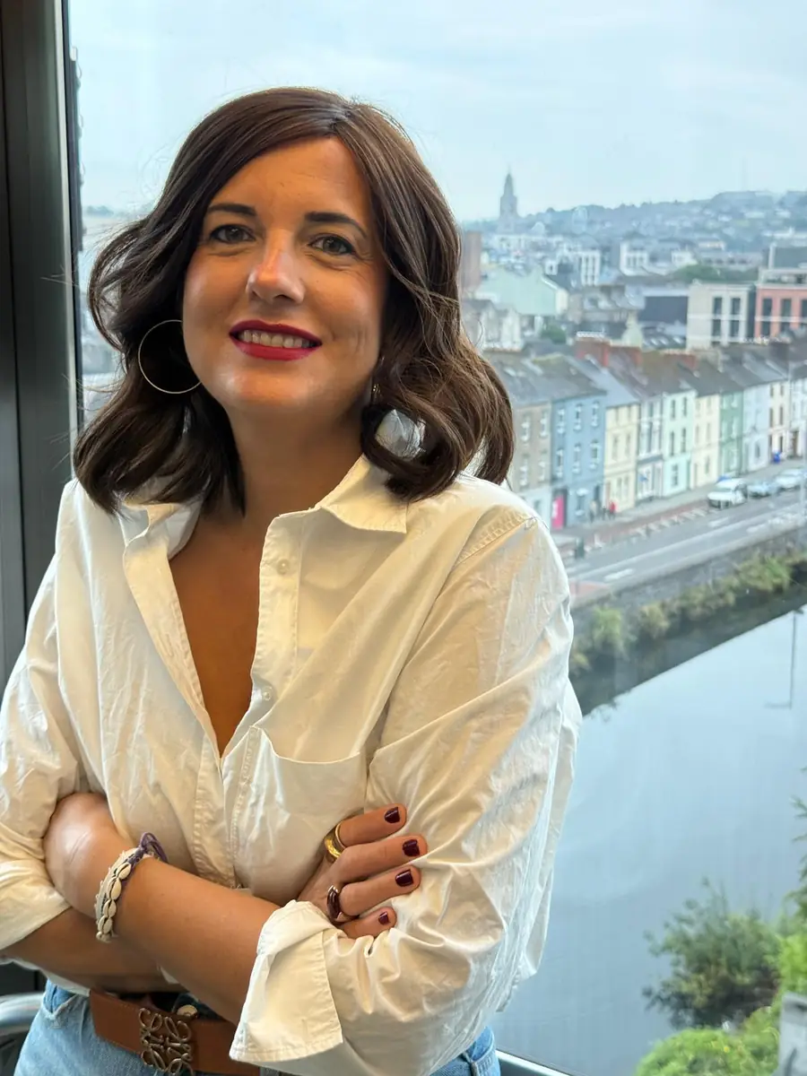 Esther junto a un ventanal con vistas a la ciudad y al río