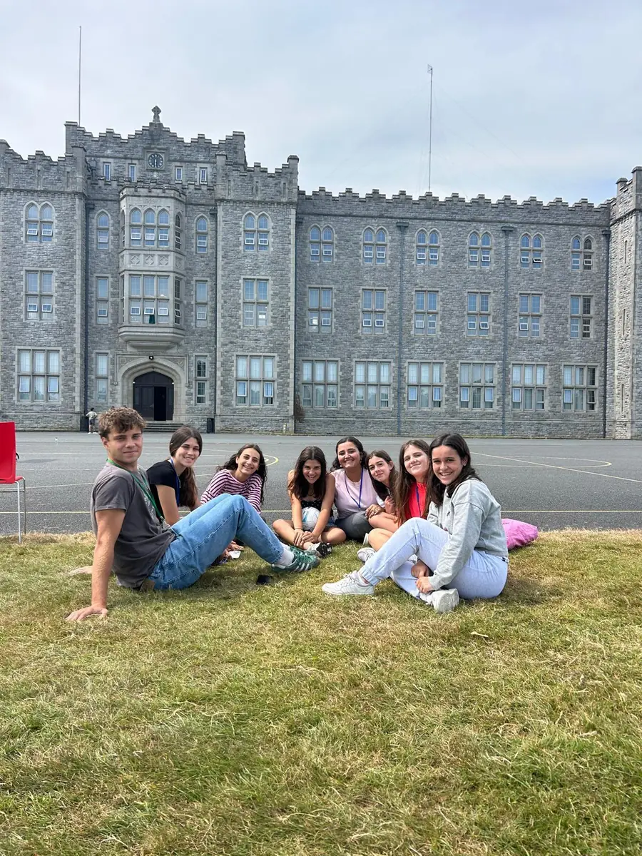 Estudiantes sentados en el césped frente a un colegio de Irlanda