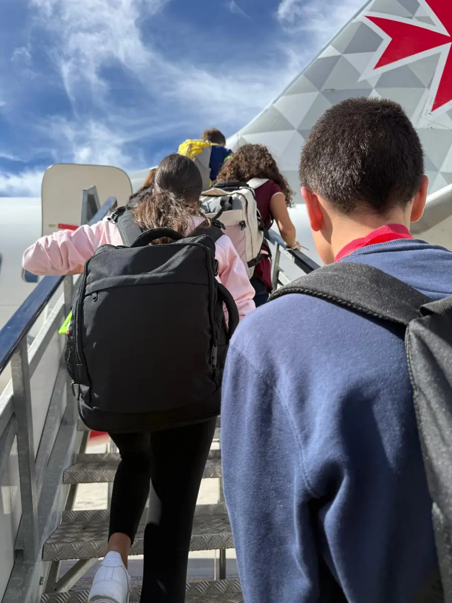 Estudiantes con sus mochilas subiendo a un avión